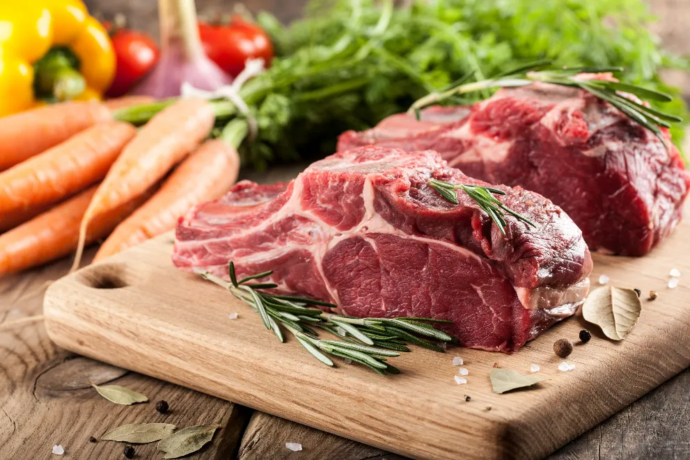 Raw beef meat on cutting board and fresh vegetables